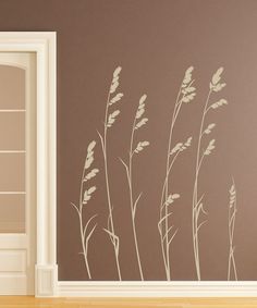 a wall decal with tall grass blowing in the wind on a brown wall next to a white door