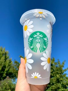 someone holding up a starbucks cup with daisies on it