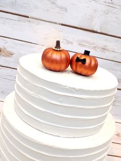 two pumpkins sitting on top of a white cake