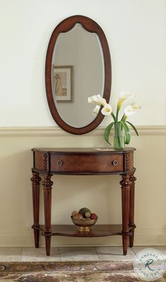 a wooden table with a mirror and vase on it