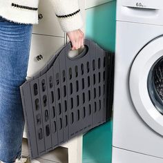 a woman is holding a laundry basket next to a washing machine