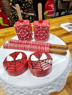 two red cupcakes on a white plate with spider web decorations and cinnamon sticks