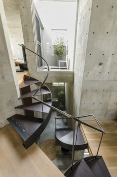 a spiral staircase in the middle of a room next to a table and chair with a potted plant on it