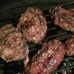 hamburgers and burger patties cooking on an outdoor grill