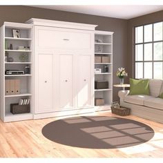 a living room filled with furniture and bookshelves on top of wooden flooring