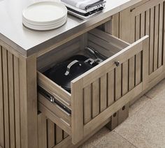 a kitchen cabinet with an open drawer containing pots and pans on top of it