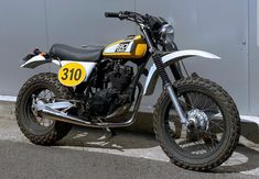 a yellow and black motorcycle parked in front of a building next to a gray wall