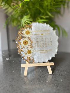 a calendar with flowers on it sitting on a table next to a potted plant