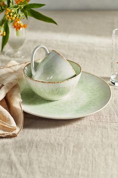 there is a tea cup and saucer set on the table next to some glasses