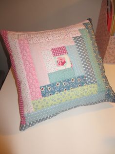 a decorative pillow made from patchwork material on a table with a lamp in the background