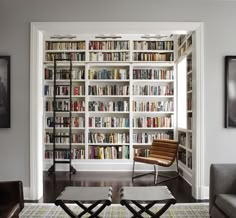 a living room filled with lots of books on top of a white book shelf next to a window