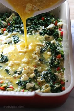 a casserole dish with cheese being poured into it and broccoli in the background