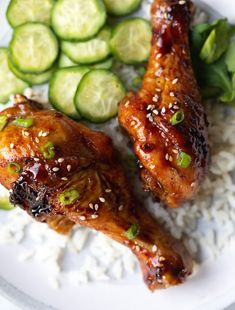 two pieces of chicken on top of rice with cucumbers