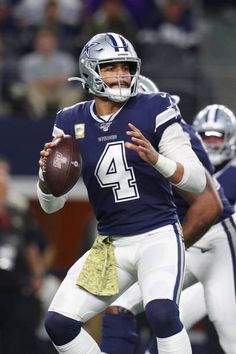 a football player holding a ball in his hand and wearing a helmet with the number four on it