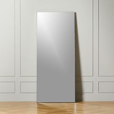 a mirror on the floor in front of a wall with white paneling and wooden floors