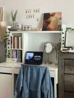 a laptop computer sitting on top of a white desk next to a book shelf filled with books