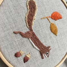 an embroidered piece of art with leaves and acorns on it's side