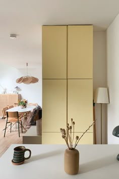 a vase filled with flowers sitting on top of a white counter next to a lamp