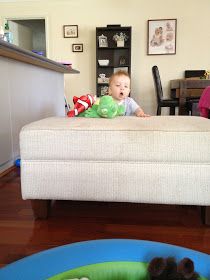 a baby sitting in a toy boat on the floor next to a table and chair