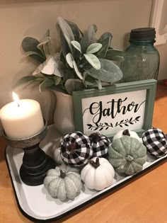 a tray with pumpkins and candles on top of a table next to a sign that says gather