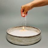 a person's hand is sprinkling water into a bowl