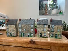 three small houses sitting on top of a wooden table