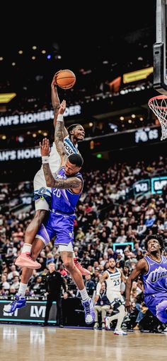 the basketball player is going to dunk the ball in front of the other players