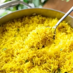 a pot full of yellow rice with a spoon in it