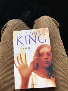 a book sitting on top of a couch next to a person's feet and hand