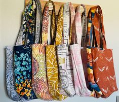 an assortment of colorful ties hanging on a wooden rack in front of a white wall