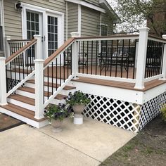 a porch with white railings and wooden steps leading up to the front door on a house