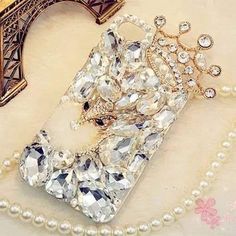 an iphone case with pearls and a crown on the front, next to a pearl necklace