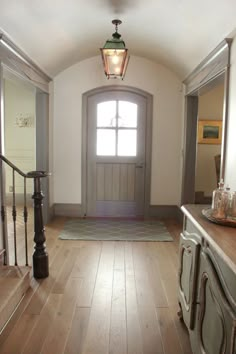 an entryway with a light fixture and wooden flooring in front of a door