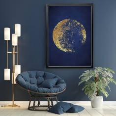 a living room with blue walls and a gold moon painting on the wall next to a chair