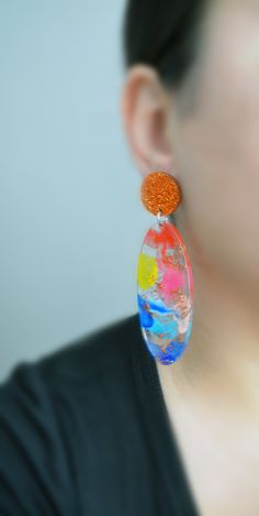 a close up of a person wearing some kind of earring with an orange and blue design on it