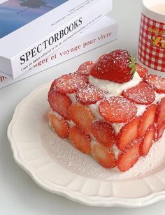 a white plate topped with strawberry shortcakes next to a cup of tea and a book