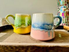 two coffee mugs sitting on top of a wooden tray next to eachother