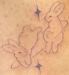 a tattoo on the back of a woman's stomach with two rabbits and stars