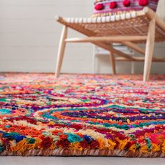 a multicolored rug on the floor with a wooden chair in the back ground