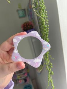 a person holding a small mirror in front of a wall with flowers and plants on it