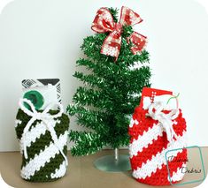 two knitted christmas stockings sitting next to each other on a wooden table with a small tree in the background