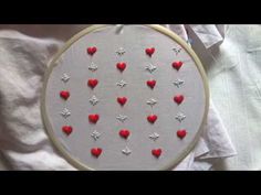 a close up of a embroidery on a white cloth with red hearts and silver stars