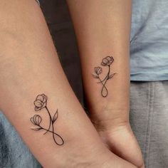 two people with matching tattoos on their arms holding each other's hands, one has a flower and the other has a cross