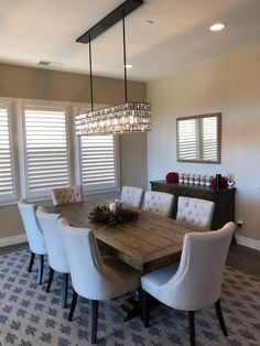 a dining room table with white chairs and a chandelier