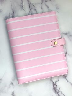 a pink and white striped notebook sitting on top of a marble counter