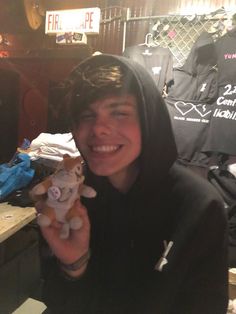 a young man holding a stuffed animal in his right hand and smiling at the camera