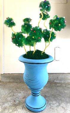 a blue vase filled with green plants on top of a floor