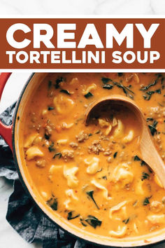 creamy tortellini soup in a red pot with a wooden spoon on the side