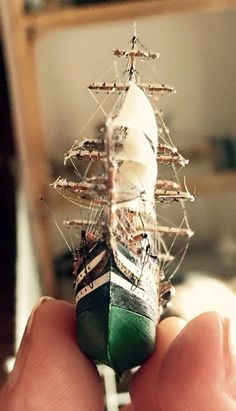 a hand holding a small model ship in it's palm