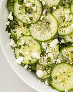 cucumber and feta salad in a white bowl on top of a table